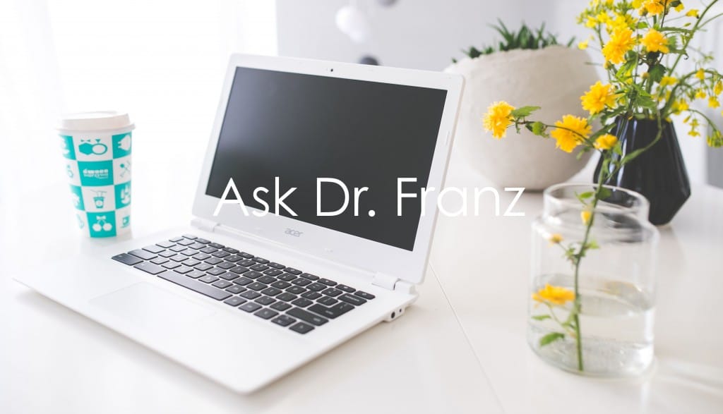 Ask Dr. Franz: Laptop, flowers, and coffee on a clean white desk, ready for consultation. August 12, 2018.