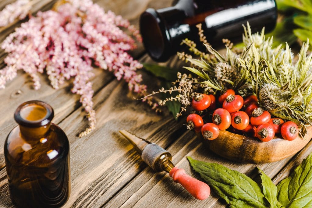 Natural rash remedies: Flowers, berries, and glass jars on a wooden tabletop suggest home treatments for skin irritation.