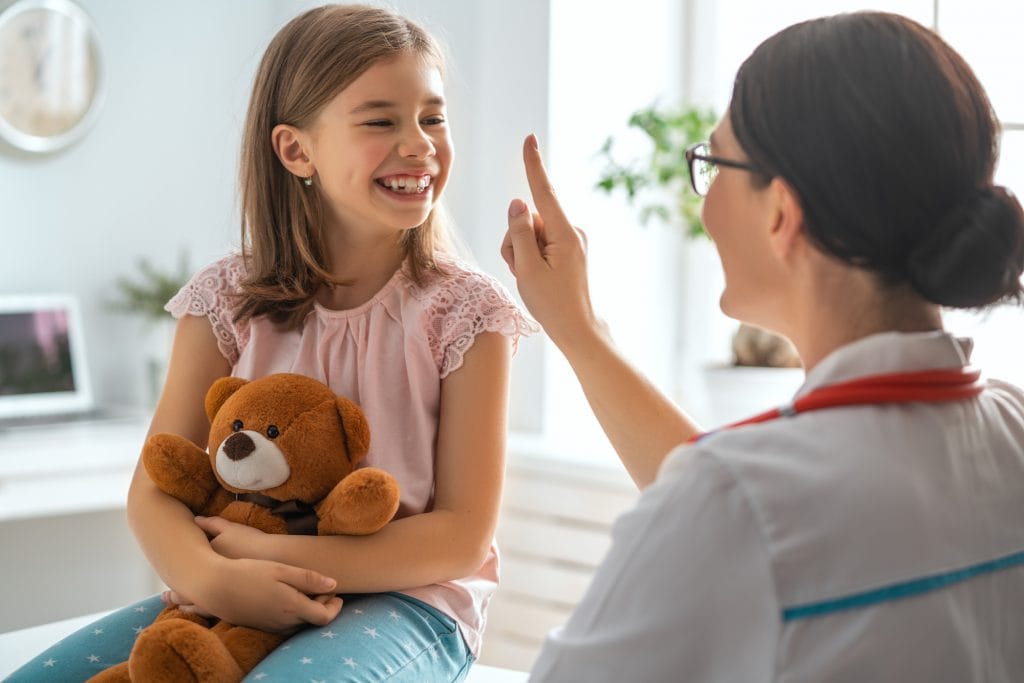 Doctor examining child with teddy bear. Patient testimonials for pediatric care, health and wellness services.