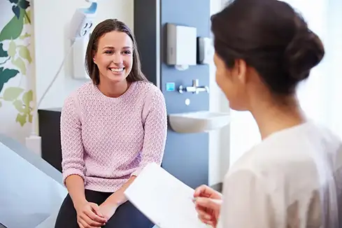 Woman smiling, discussing anxiety treatment with doctor. Mental health care and support concept.