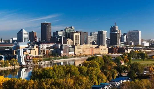Virtual Visits Minnesota: Skyline view of downtown Minneapolis with river and fall foliage. Urban tourism and scenic beauty.