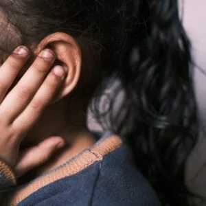 Child holding ear, indicating ear ache. Ears with No Tears Bundle concept. Focus on ear and hand.